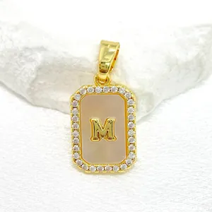 Gros plan du pendentif doré lettre M avec nacre blanche et zircons incrustés