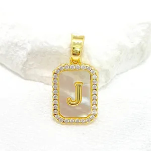 Détail macro du pendentif lettre J doré avec incrustation de nacre et zircons blancs