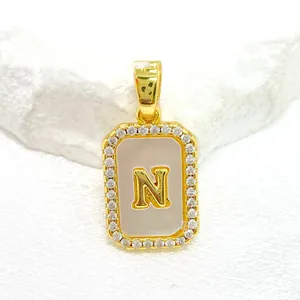 Détail d'un pendentif carré doré avec nacre, zircons et lettre N incrustée