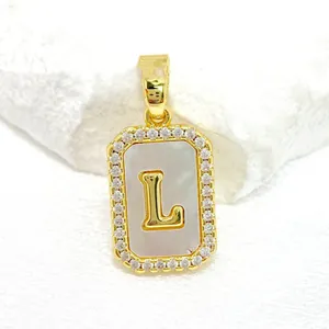 Macro d'un pendentif lettre L carrée dorée avec nacre et oxydes de zirconium brillants