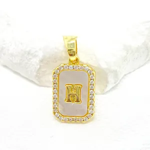 Détail du pendentif rectangulaire doré avec incrustation de nacre, cadre diamanté et lettre H