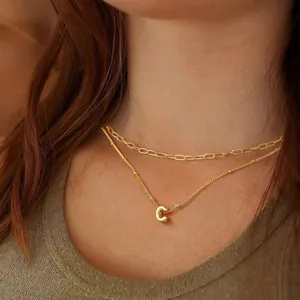 Layered gold necklace featuring a paperclip chain and a polished letter C pendant