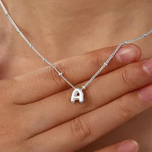Macro detail of silver A-letter pendant necklace with delicate beaded chain on a model