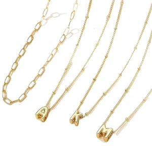 Layered gold-plated paperclip and bead necklaces featuring A, K, and M letter pendants