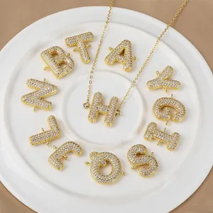 Parure de collier avec lettres cursives plaqué or et zircons sur une assiette blanche
