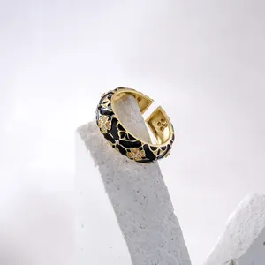 Close-up of gold adjustable ring with black enamel four-leaf clover and zircon inlay