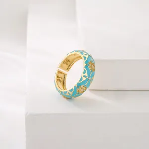 Macro detail of a blue enamel flower ring with gold finish and open adjustable band