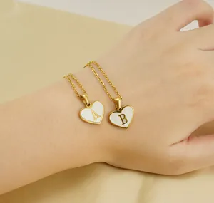 Detailed shot of two heart-shaped shell alphabet pendants on golden necklaces