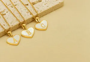 Close-up of gold heart shell pendants with letters A, B, C on delicate cable chains