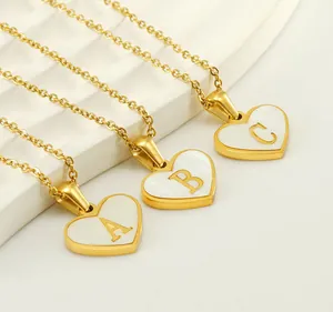 Detail of heart shell necklaces with gold initial letters A B and C on white background