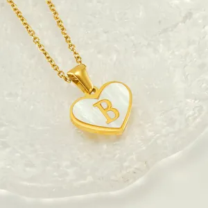 Macro shot of gold heart pendant necklace featuring shell inlay and metal letter B