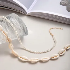 Detail of layered necklace featuring white pearls, natural sea shells, and gold clasp