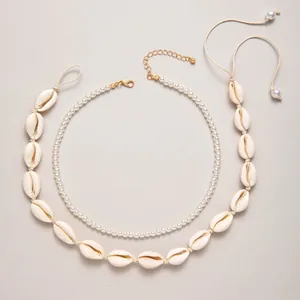 Detailed view of layered white pearl necklace and handcrafted shell choker on grey background