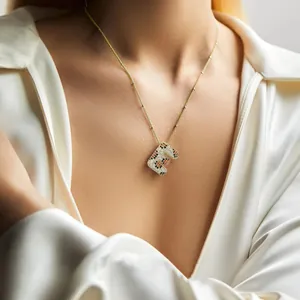 Dettaglio del ciondolo lettera E placcato oro 18k con pietre maculate su camicia di seta