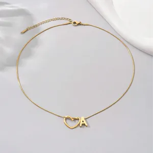 Detail of gold snake chain necklace featuring letter A and heart pendants with lobster clasp