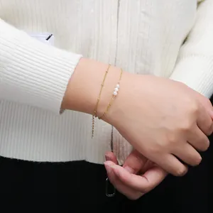 Détail d'un bracelet double couche en or avec maillons trombone et trois perles blanches