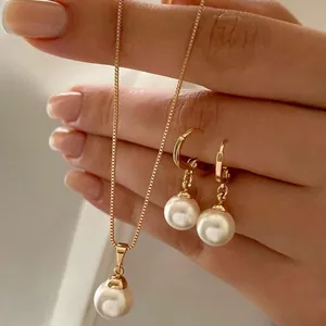 Elegant gold pearl jewelry set featuring a pendant necklace and earrings on a hand