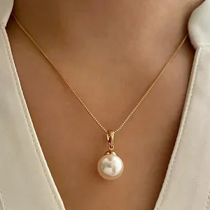 Close-up of elegant gold box chain necklace with a single round white pearl pendant