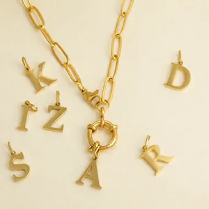 Macro detail of gold paperclip chain necklace with various alphabet initial pendants