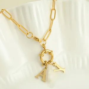 Detail of golden paperclip chain necklace with decorative ring and A-Y letter pendants