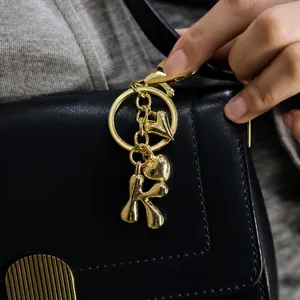Detail eines goldenen Buchstaben-K-Schlüsselanhängers mit Herzanhängern an einer Tasche