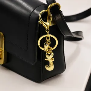 Detail eines 18k vergoldeten Bubble-Buchstaben J und Herz-Schlüsselanhängers an Tasche