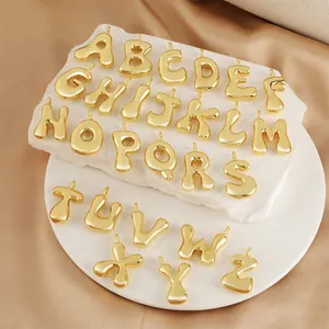 Détail de 26 breloques lettres dorées 18 carats sur marbre blanc et satin soyeux