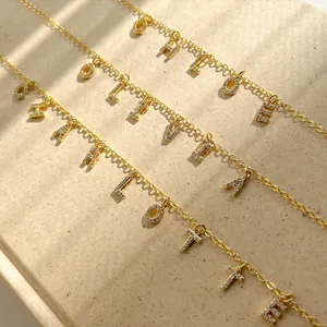 Nahaufnahme von drei goldenen Namensketten mit Zirkonia-Steinen auf strukturiertem Grund