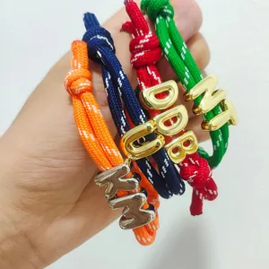 Colorful braided rope bracelets with gold bubble letter charms in orange navy and red