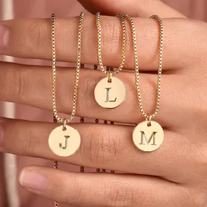 Detailansicht goldener Halsketten mit eingravierten Buchstaben J, L und M auf Schichten