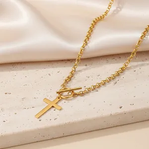 Detail of gold cross pendant necklace with modern OT toggle clasp on stone surface
