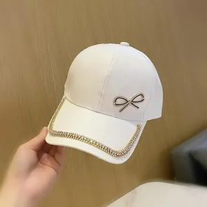 Détail de casquette blanche avec nœud en strass et bordure en cristaux brillants
