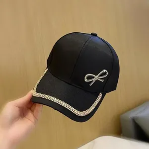 Détail d'une casquette noire avec un nœud en strass brillant et une bordure en cristaux fins