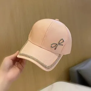 Détail d'une casquette rose avec un nœud en strass et bordure en cristaux brillants