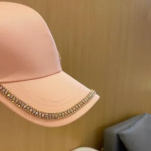 Détail macro des strass brillants sur la visière de la casquette couleur pêche