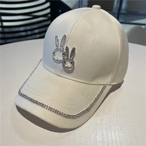 Detailed view of cream baseball cap featuring rhinestone bunny heads and crystal trim