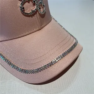 Detail of pink satin baseball cap with rhinestone brim and silver smiley face logo