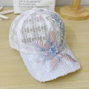 Detail view of white lace mesh baseball cap featuring 3D floral embroidery and pearls