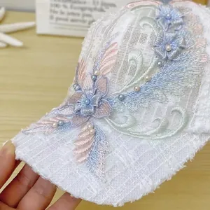 Detail of white lace baseball cap featuring 3D floral embroidery and pearl embellishments