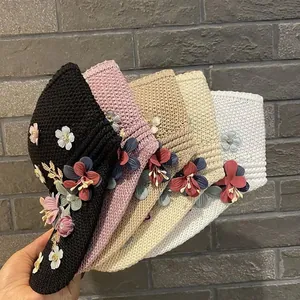 Close-up of knit sun visors in five colors featuring delicate handmade fabric flowers