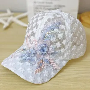 Detail aus floralem Spitzennetz und eleganter 3D-Blumenstickerei mit Perlen auf weißer Kappe