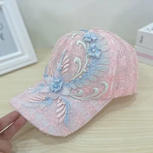 Detailed close-up of pink lace baseball cap with floral embroidery and pearl accents