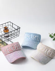 Close-up of three knitted sun visors with rhinestone SPORT text in pink, blue and beige