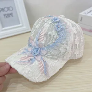 Detailed view of floral embroidery and pearl accents on a white mesh baseball cap