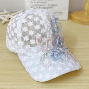 Detailansicht der weißen Spitzen-Baseballkappe mit Stickereien und Perlenverzierung