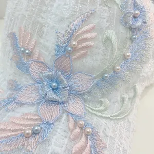 Macro shot of 3D floral embroidery and faux pearls on a white lace baseball cap