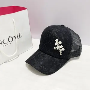Détail d'une casquette en dentelle noire avec ornements de fleurs en perles et strass
