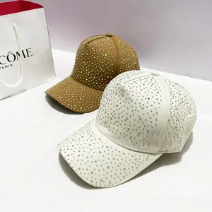 Gedetailleerde close-up van met strass versierde canvas honkbalpetten in beige en tan