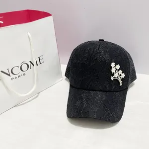 Détail de la casquette de baseball en dentelle noire avec motifs floraux et fleur brillante