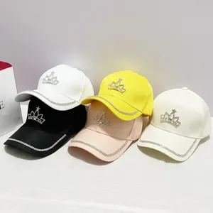 Dettaglio dei cappellini da baseball con corona di strass in nero bianco giallo e rosa